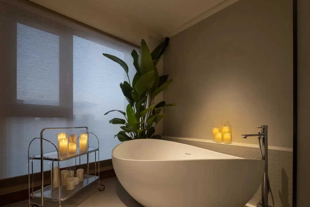 Modern bathroom featuring candles and a plant.