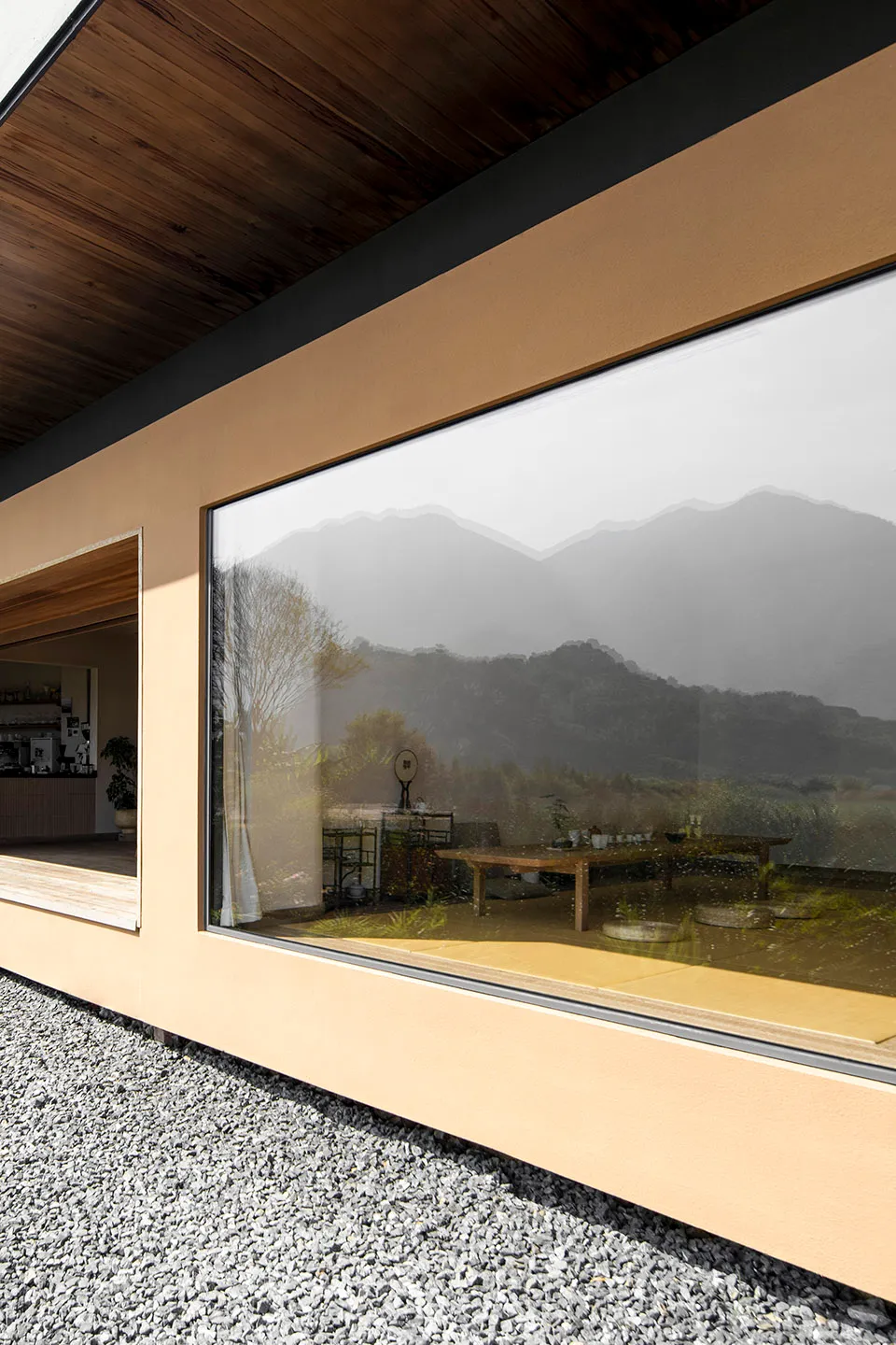A minimalist residential interior with large glass windows showing a view of mountains.