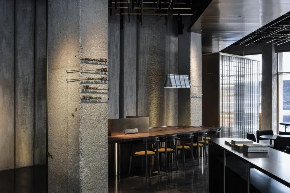A modern industrial coffee shop interior with concrete walls, glass partitions, and steel accents.