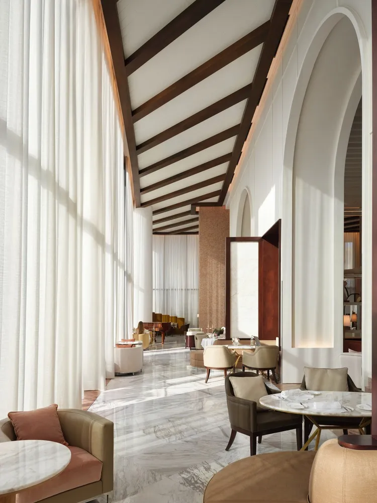 Image of a modern hotel lounge featuring glass, marble, and wood materials.