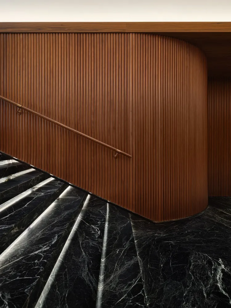 Modern staircase with black marble and wooden walls featuring a scroll design.