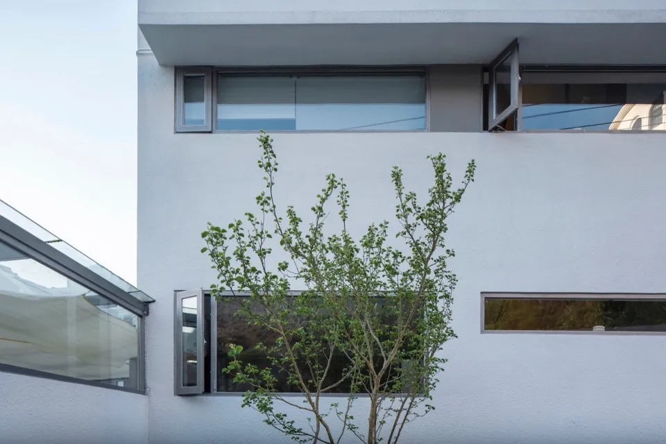 A minimalist building with white cladding and glass windows, showcasing clean lines and modern design.