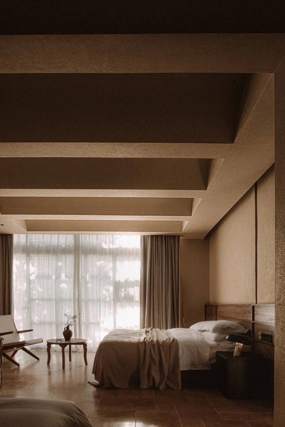 A modern bedroom with a textured wall and a video conference setup.