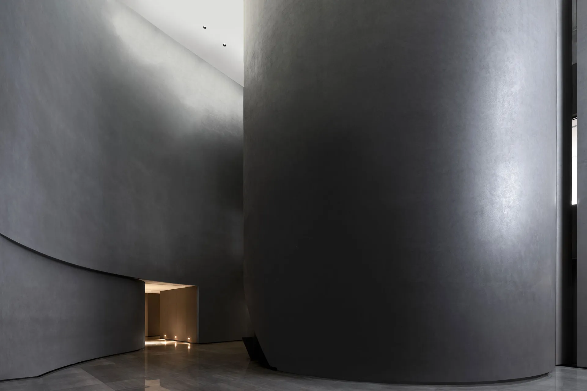 A modern lobby featuring industrial-style concrete walls and floors.