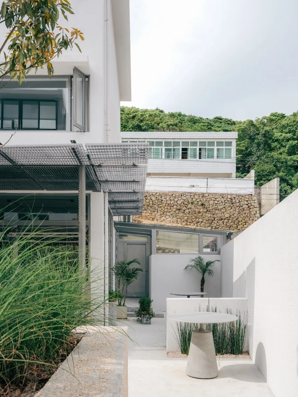 Modern outdoor space with concrete patio, plants, and minimalist furniture.