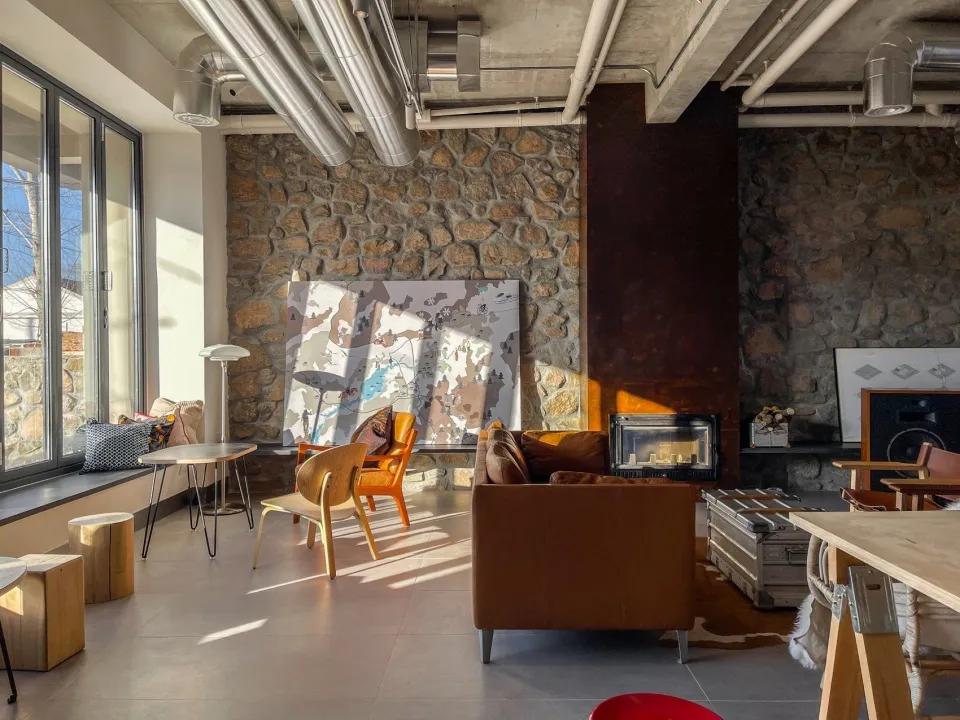An industrial-style living room with concrete, stone, and metal surfaces, featuring modern furniture and exposed ductwork.