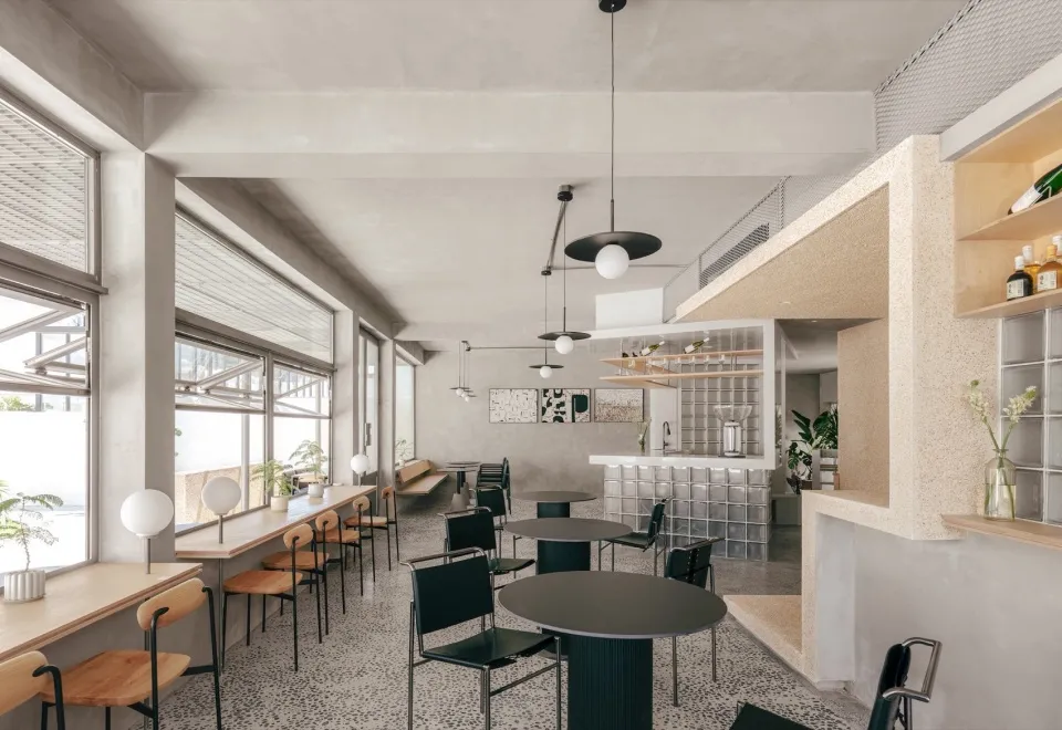 A minimalist cafe interior with concrete walls and terrazzo tiles on the floor.