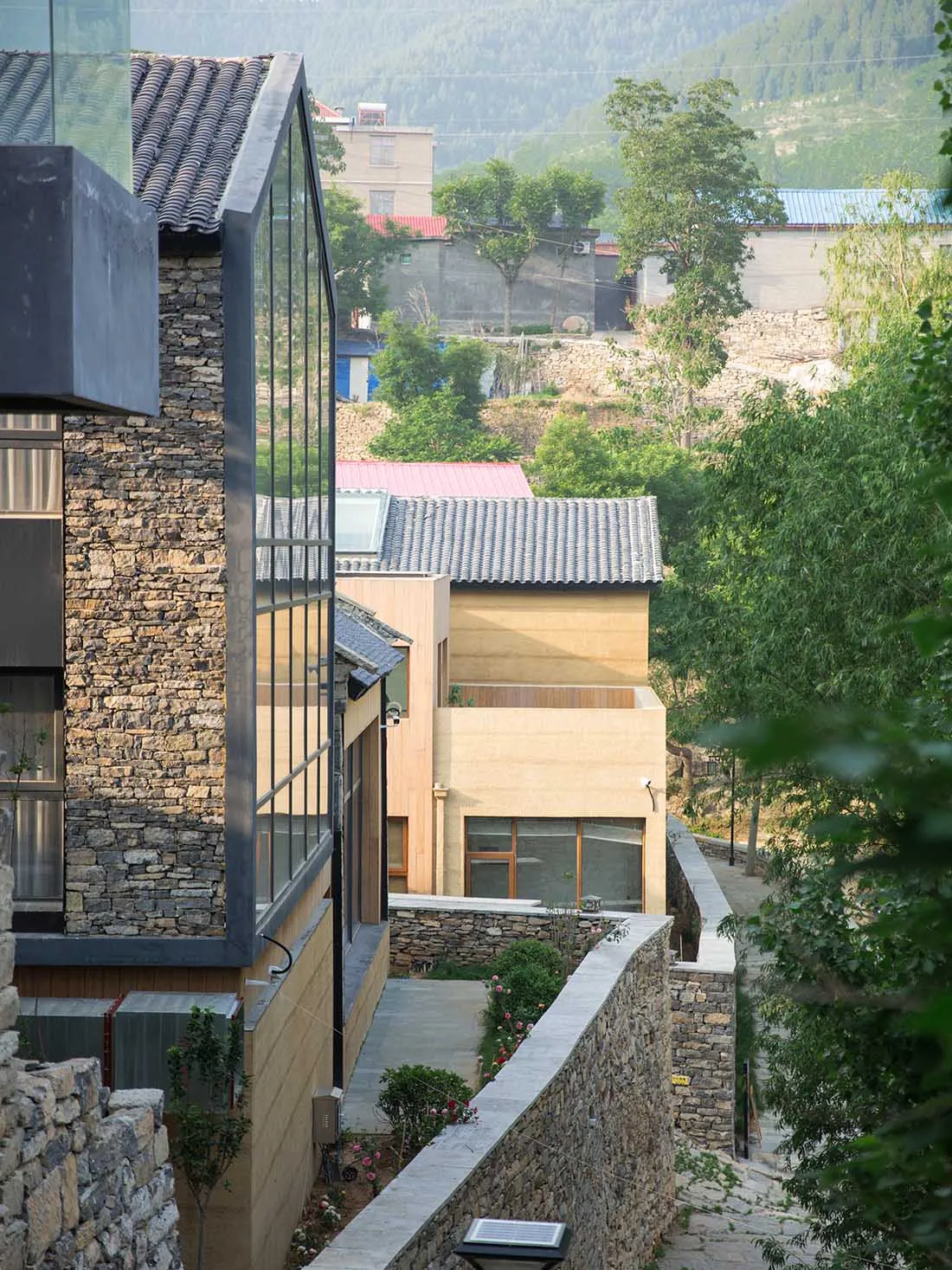 Modern residential house with wooden exterior, glass windows, stone accents, and metal roof.