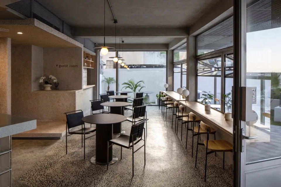 Modern restaurant interior with concrete walls, metal tables, and minimalist decor.
