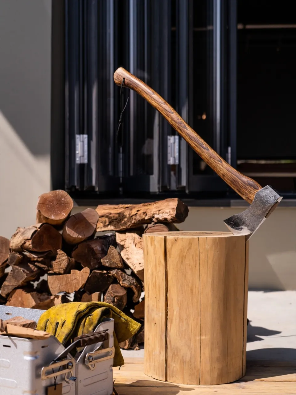Axe with wooden handle and metal blade standing in a wooden stump.