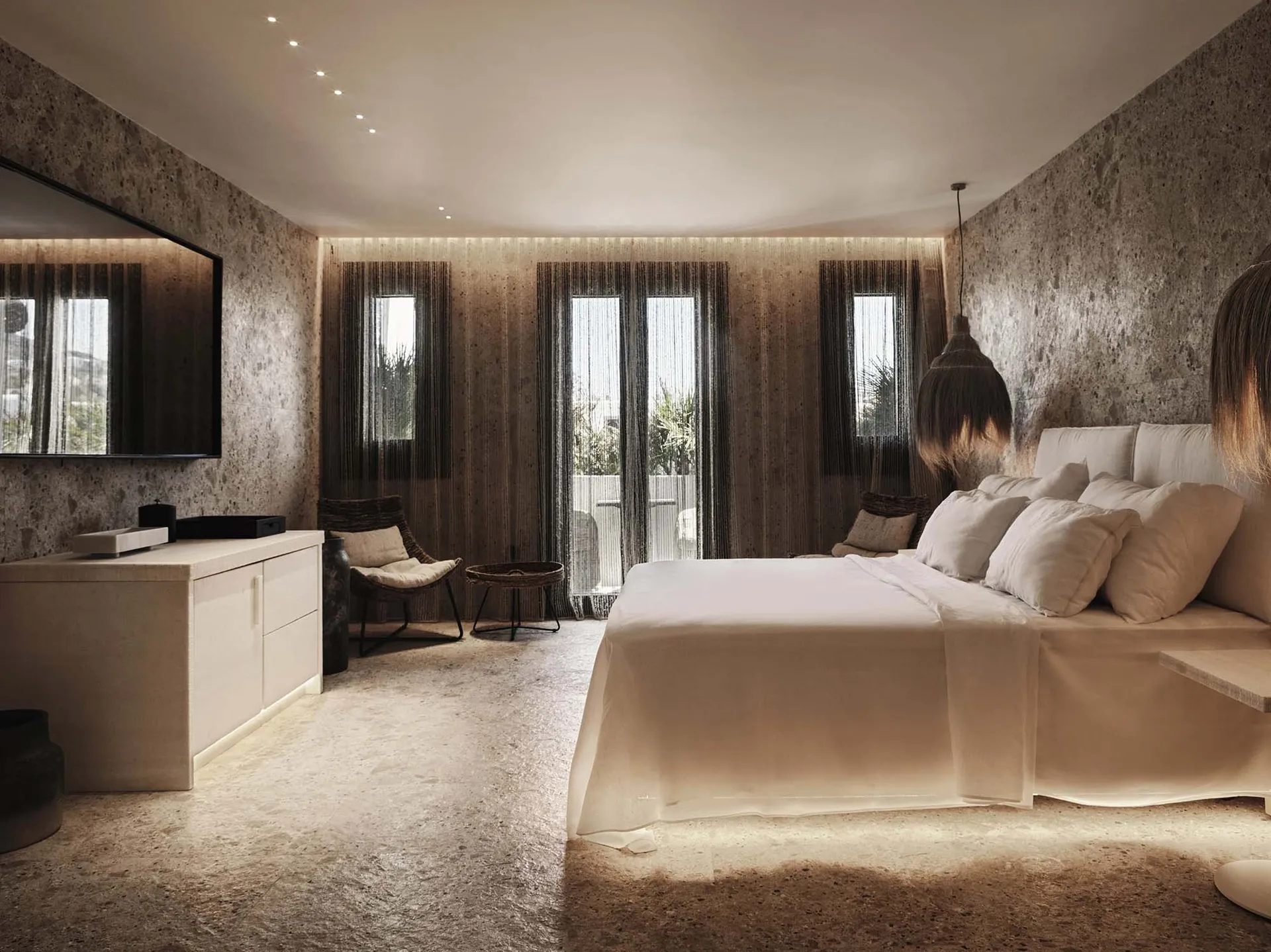 A minimalist bedroom with concrete walls and fabric soft furnishings.