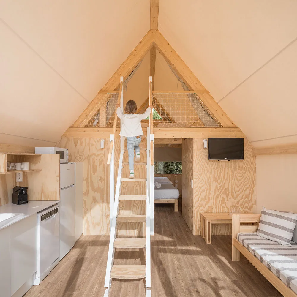 小型木屋室內採用木質牆板,並設有樓梯通往閣樓空間,配有小廚房、座位區