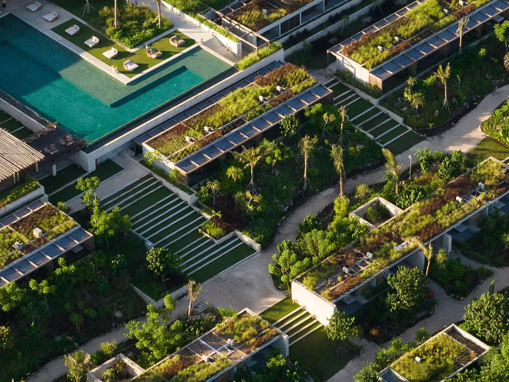 Aerial view of a residential area with green spaces, concrete pathways, and wooden structures