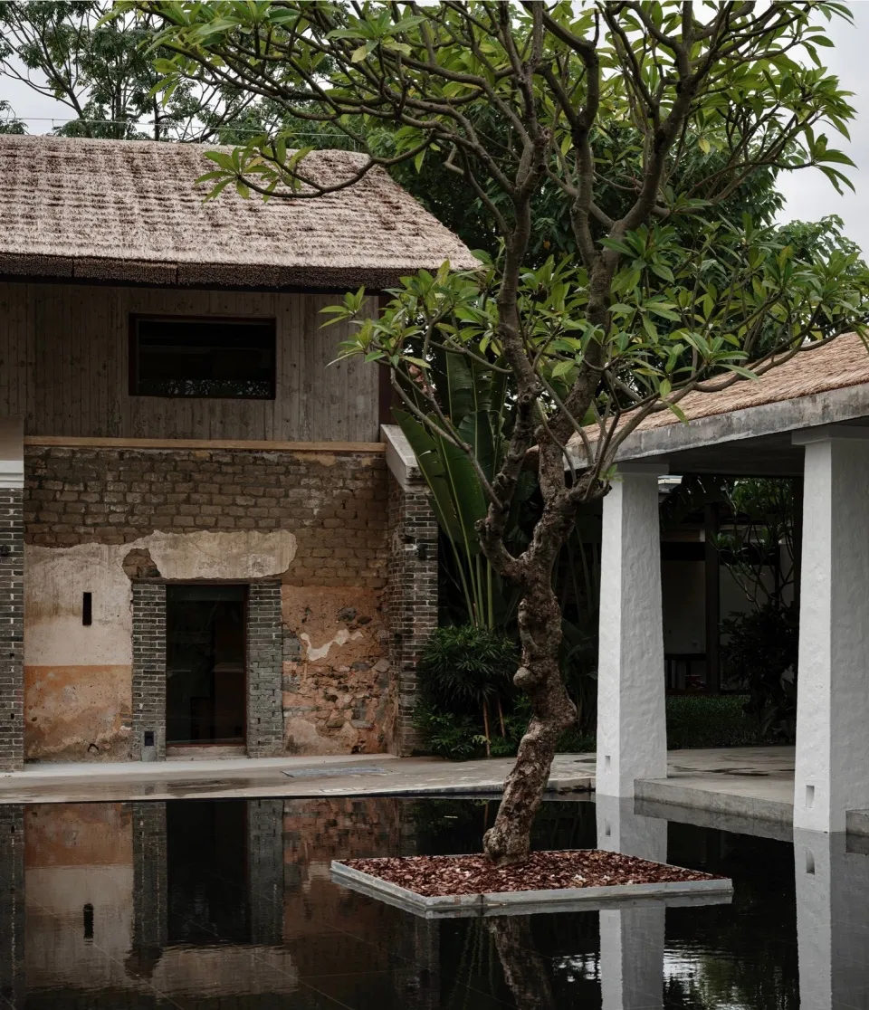 A minimalist residential exterior featuring brick, stone, and thatched roofing materials.