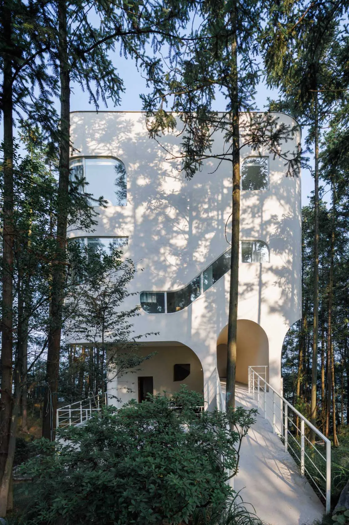 Modern, geometric architecture with concrete structure, situated in a forested area.