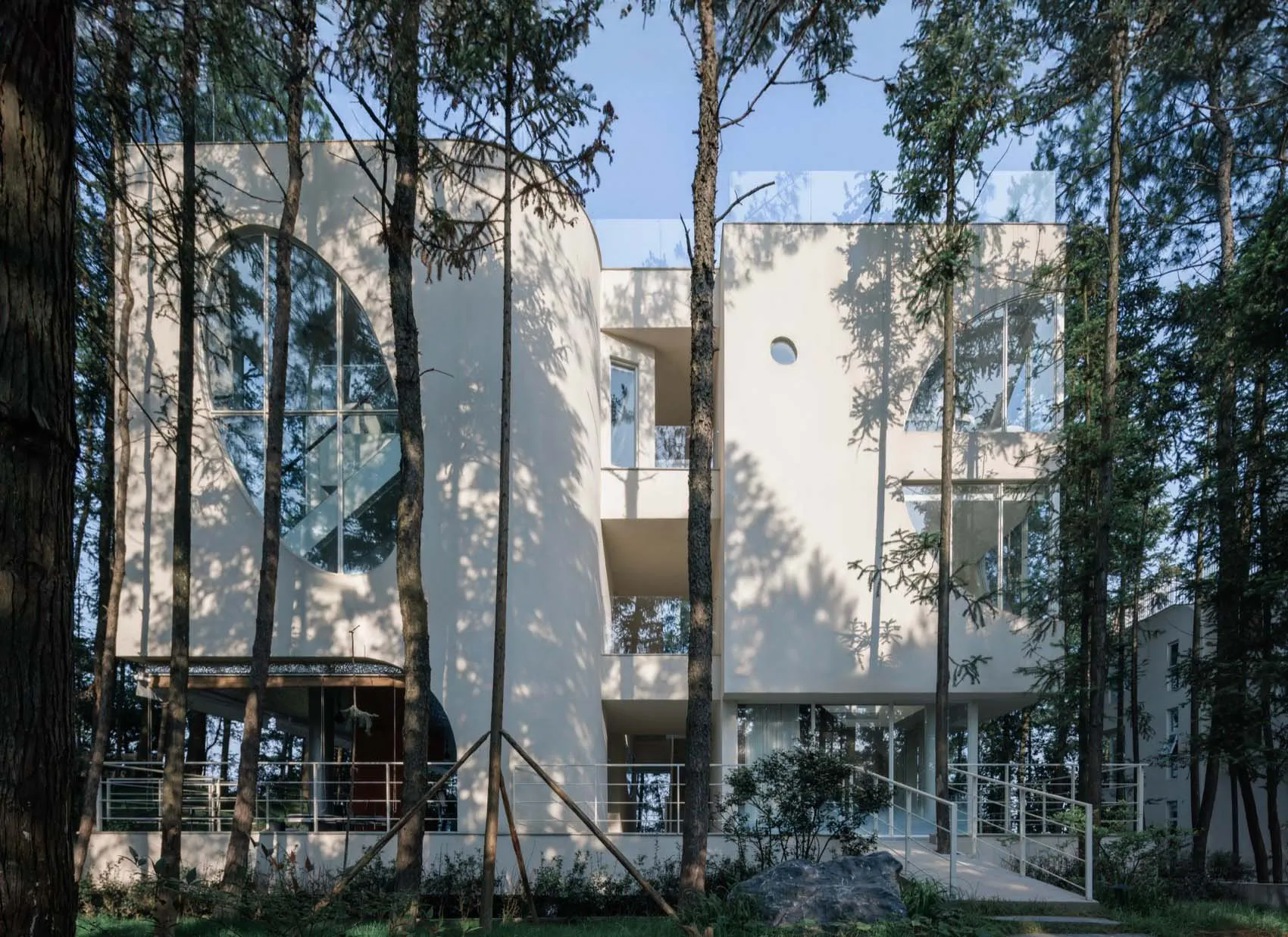 現代住宅建築以玻璃牆面與混凝土結構為特色，周圍環繞綠意。