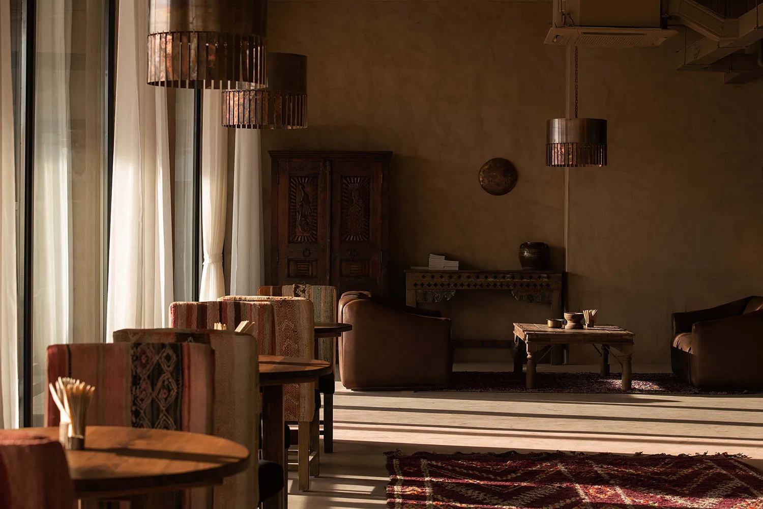 A cozy, rustic living room featuring wooden tables and plush cushions.