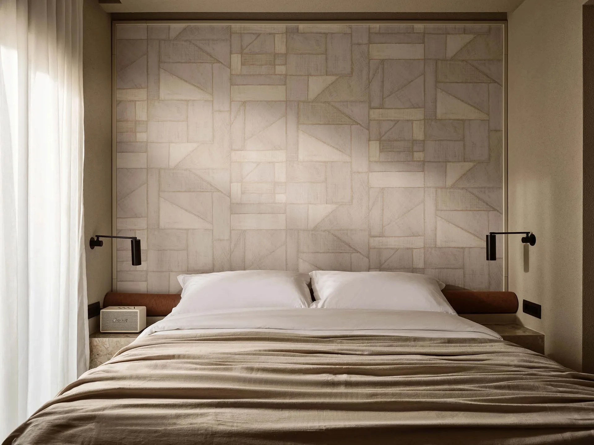 Minimalist bedroom with white textured wallpaper, white bedding, and black wall-mounted lamps.