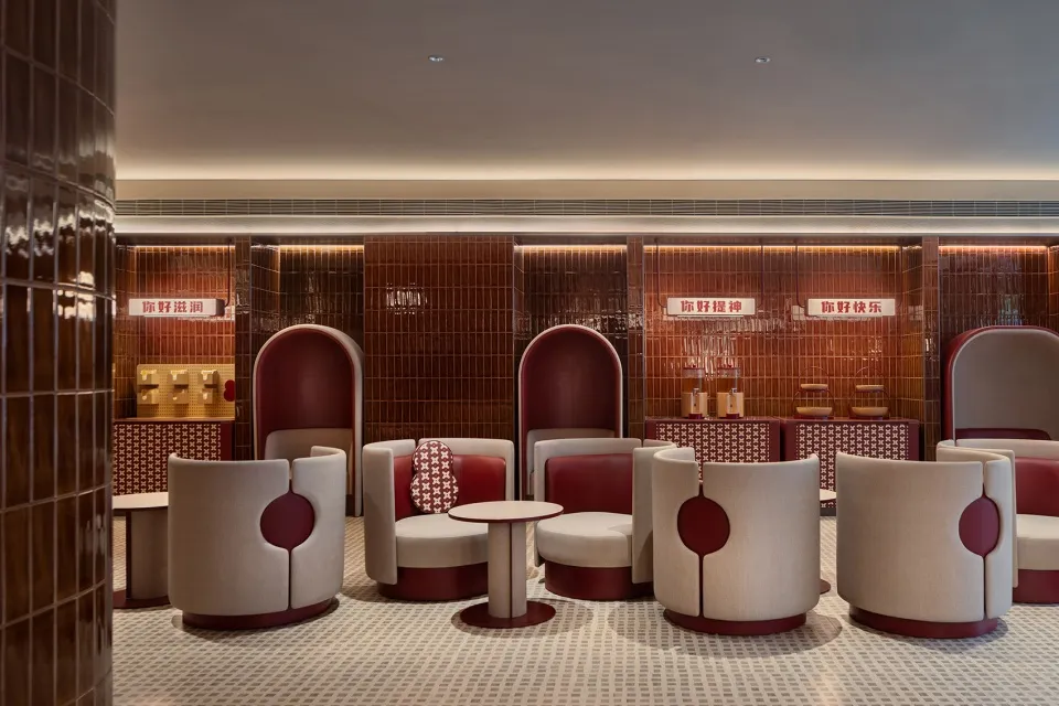 Interior of a modern coffee shop with tiled backdrop and round furniture.