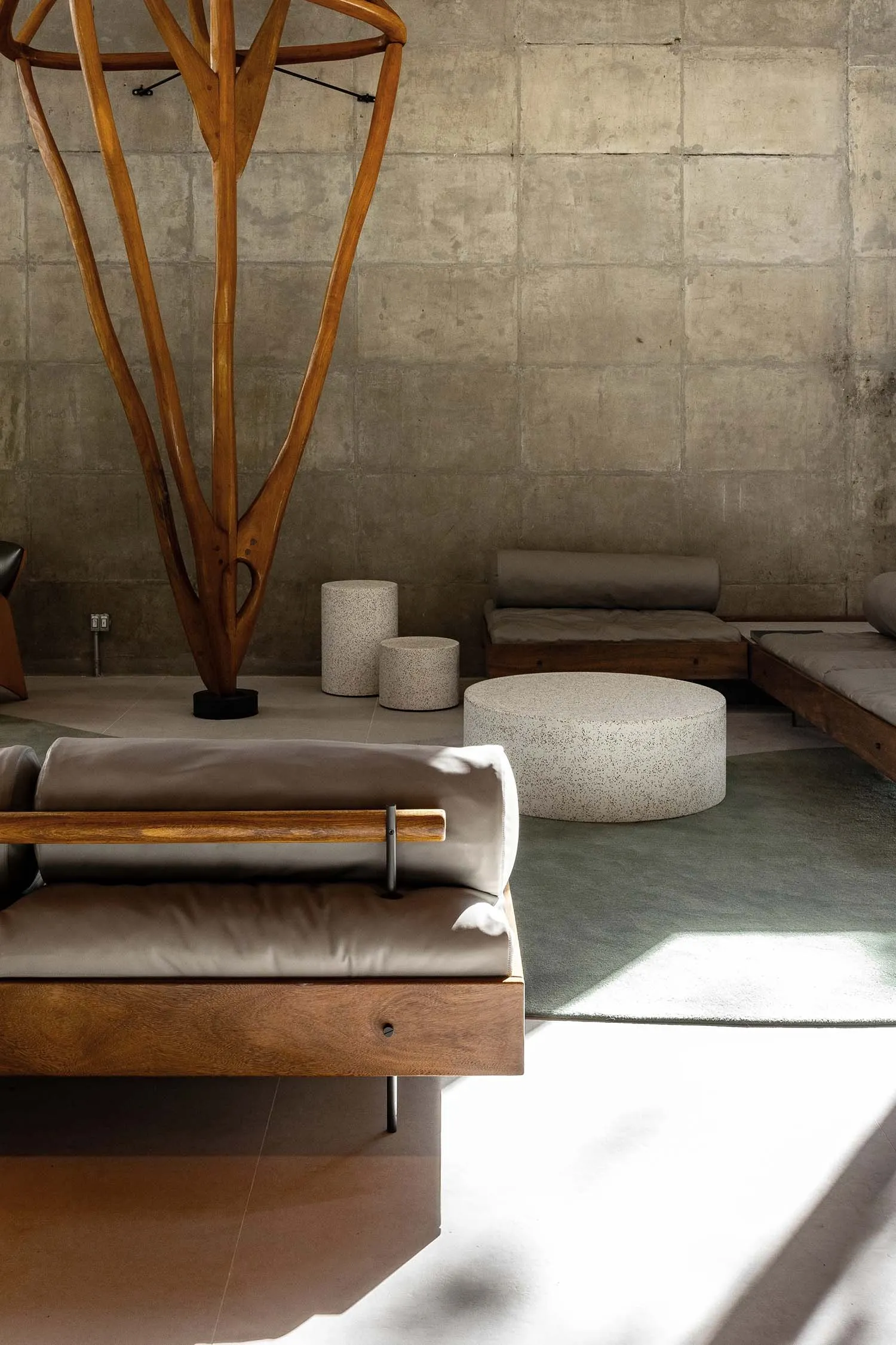 Modern living room featuring wooden furniture, concrete surfaces, and plush cushions.