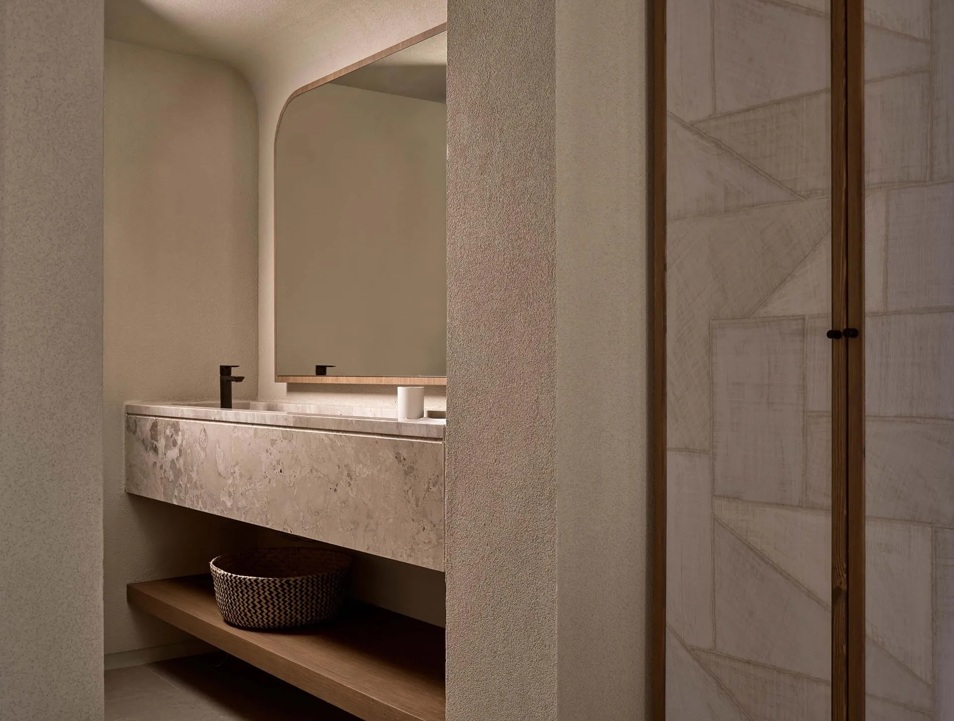 A modern minimalist bathroom featuring a marble sink with a wooden shelf underneath and a large mirror above.