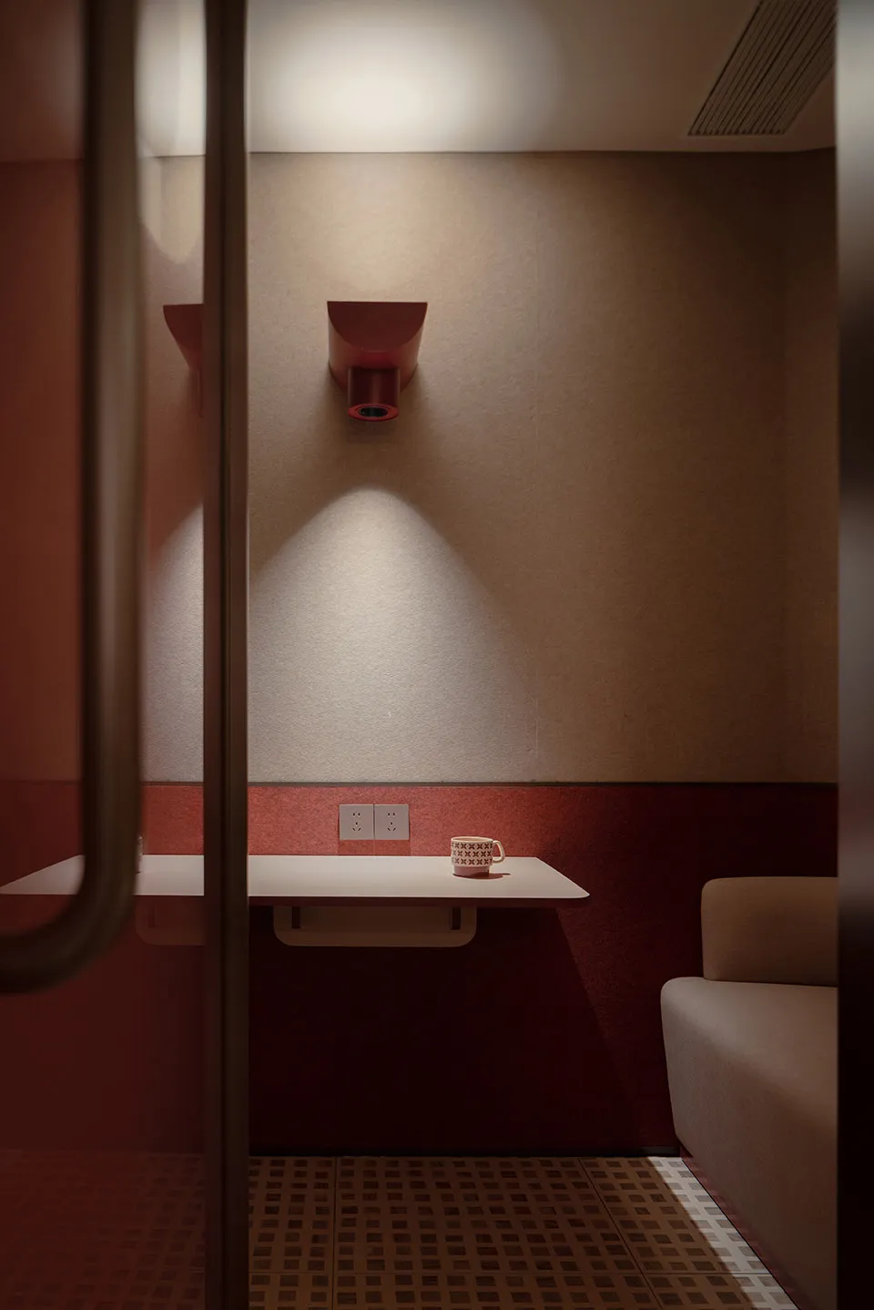 A minimalist waiting area with a single mug on a table against a neutral-toned wall and red accents.