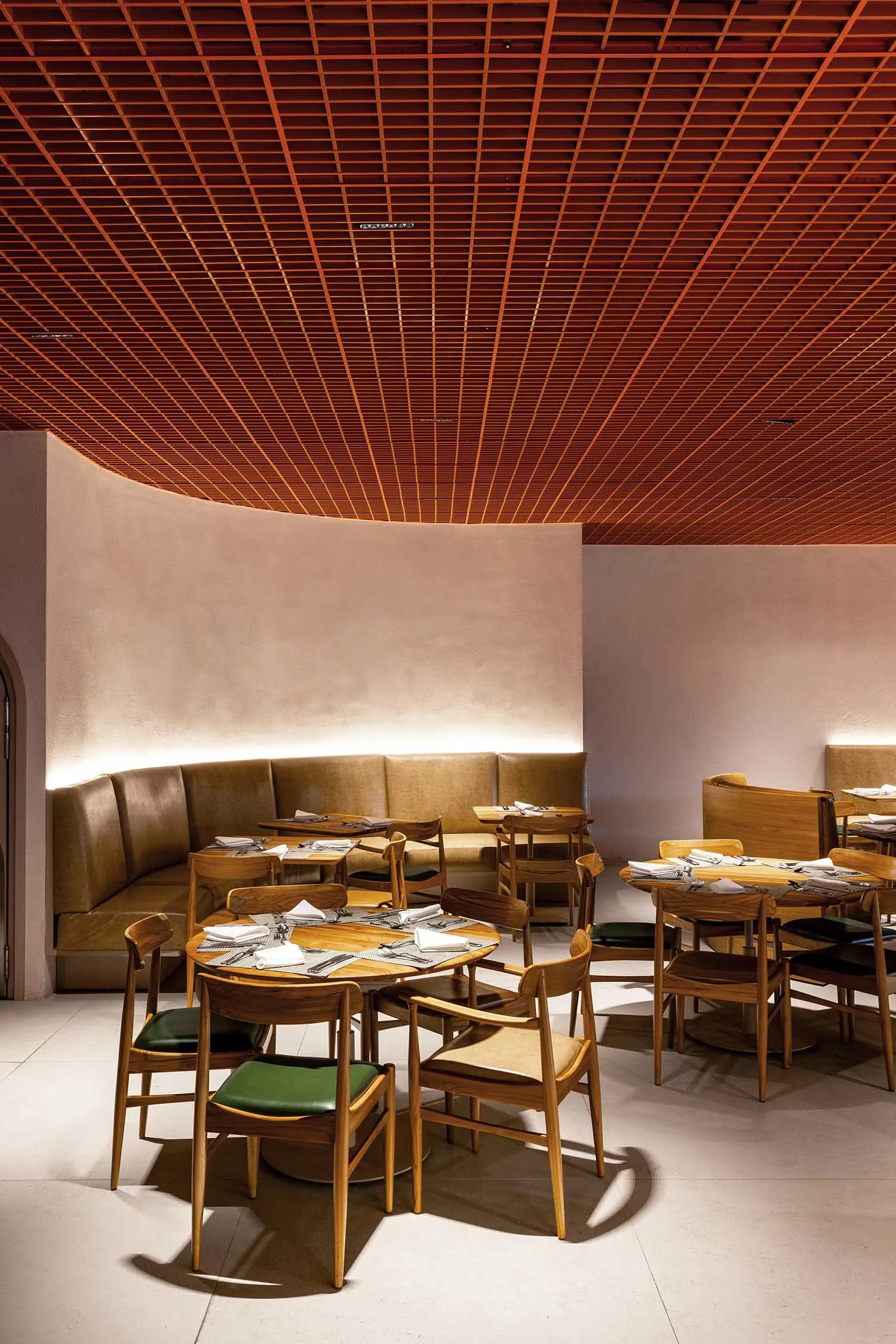 Modern restaurant interior with wooden tables, chairs, and leather seating.