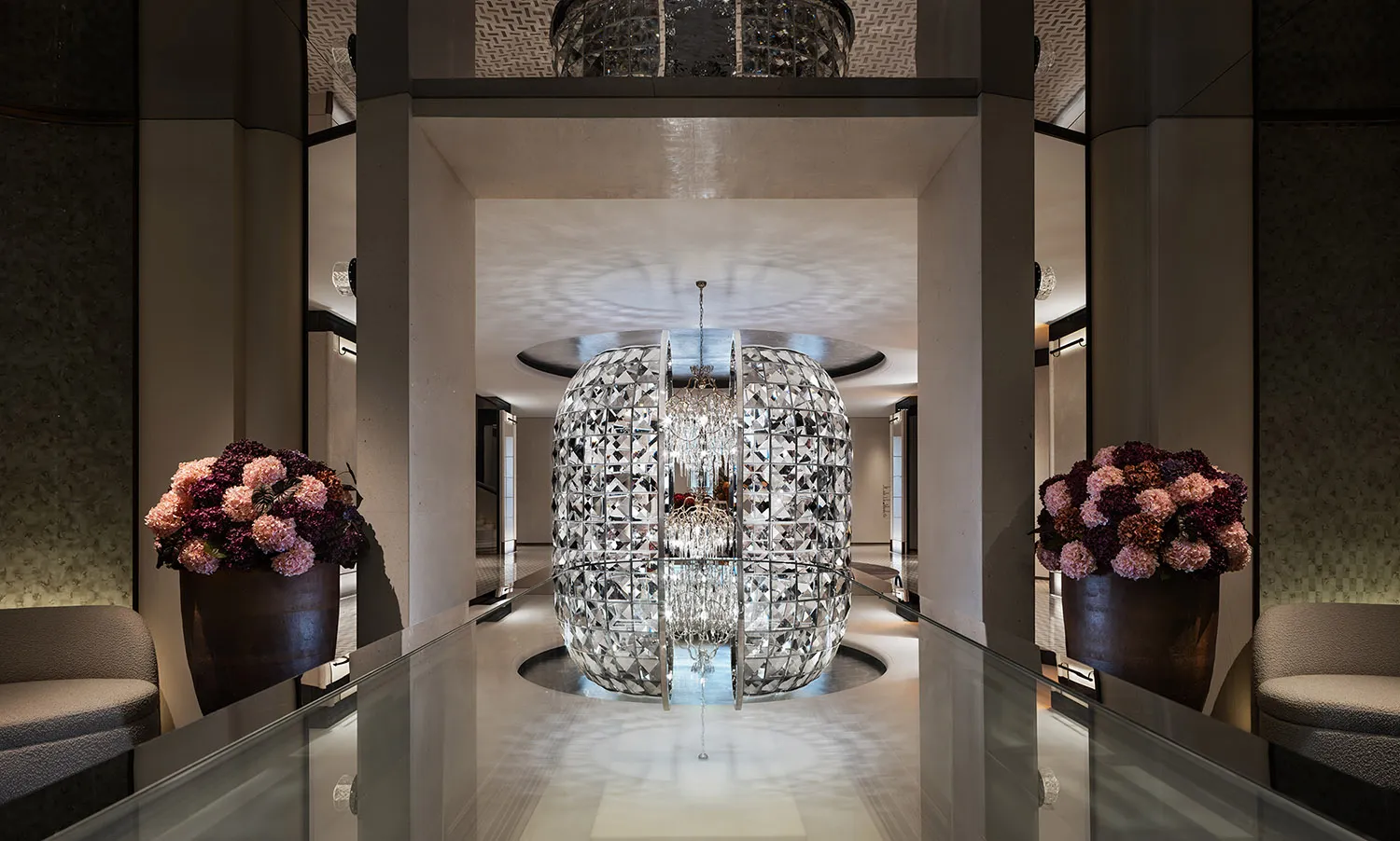 A grand, elegant hotel lobby featuring a large, ornate glass sphere at its centerpiece.