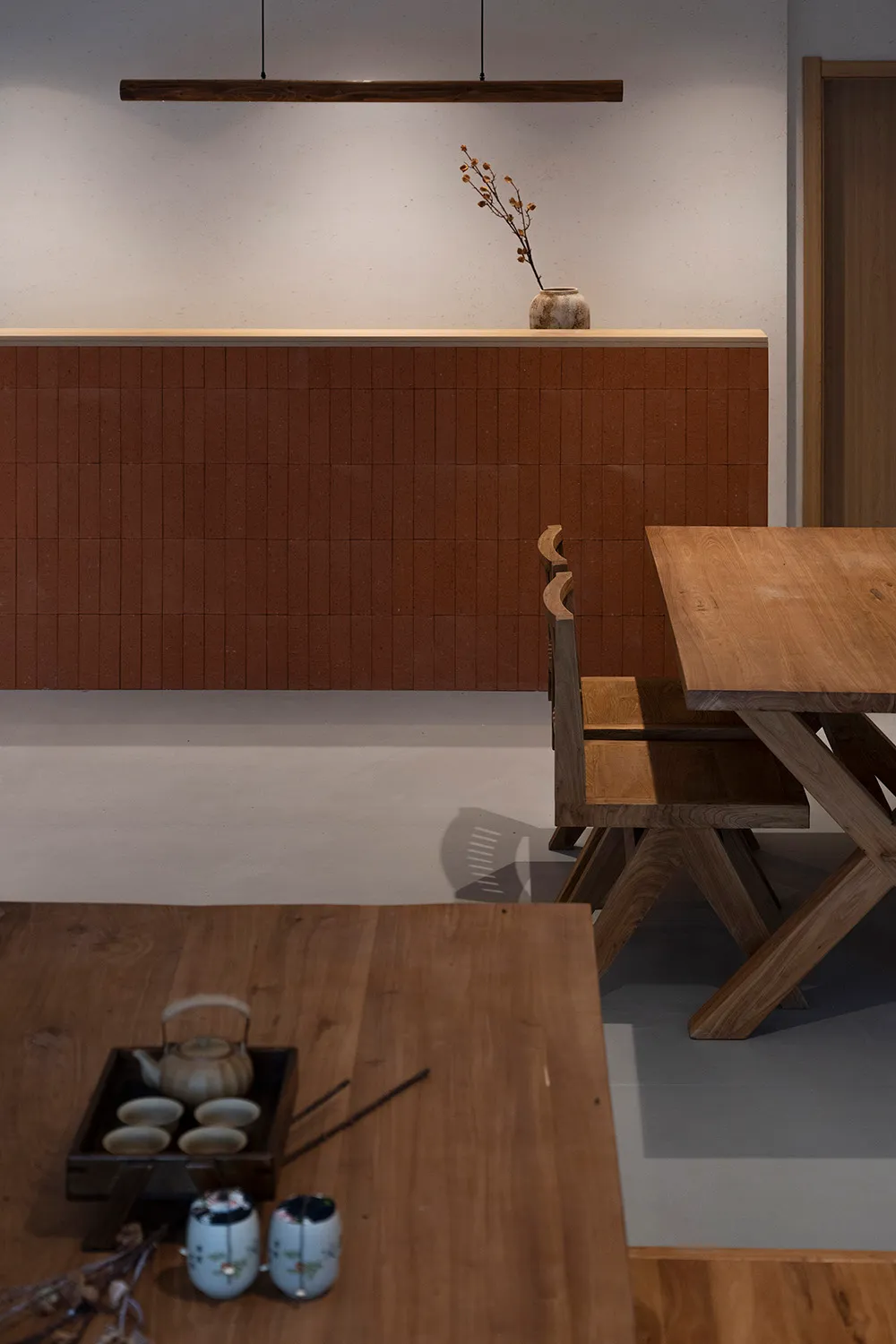 A minimalist dining room featuring wooden furniture and a wooden table with tea set and chopsticks.