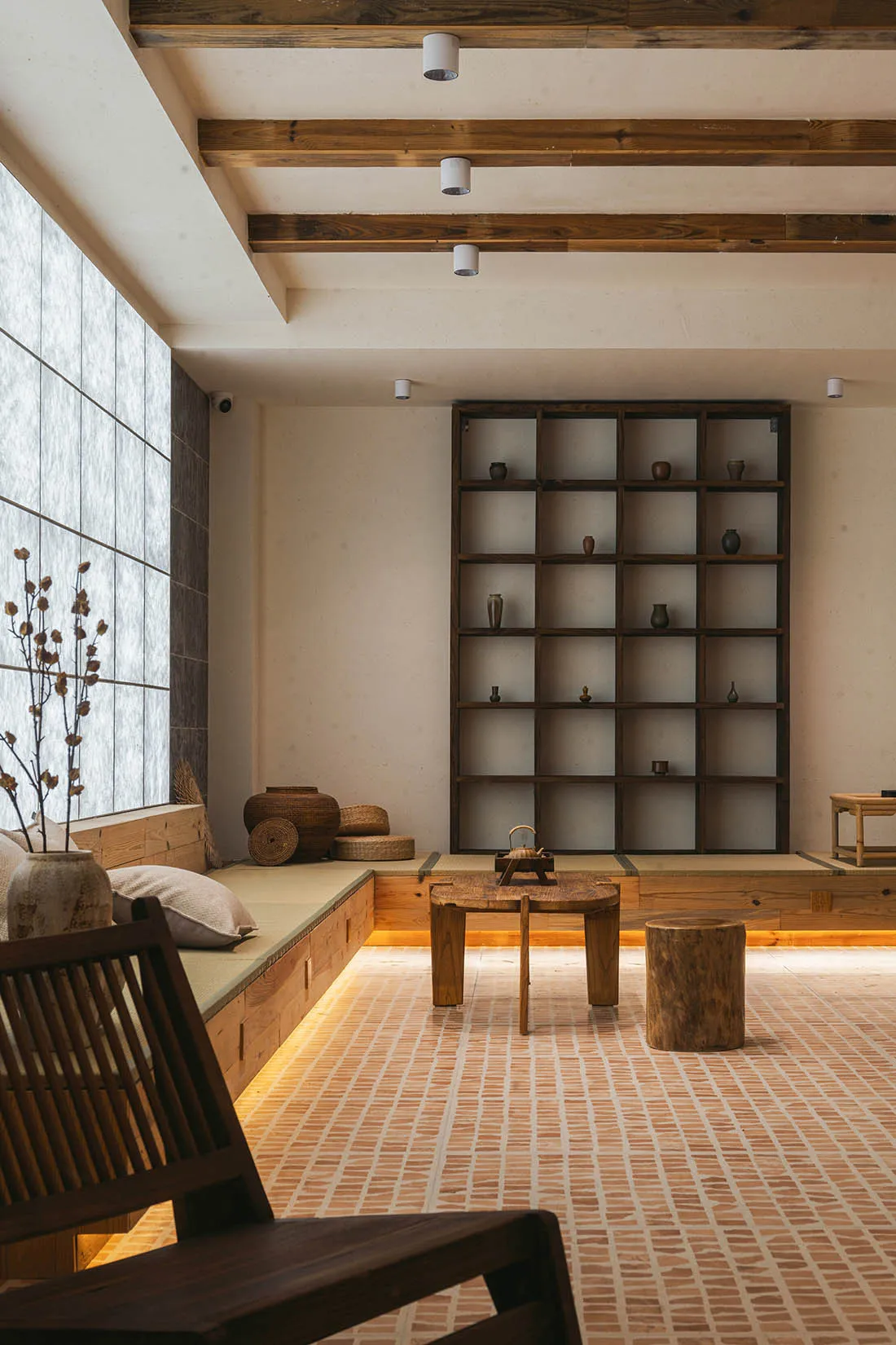 A modern living room with a wooden floor, low wooden furniture, and a large window.