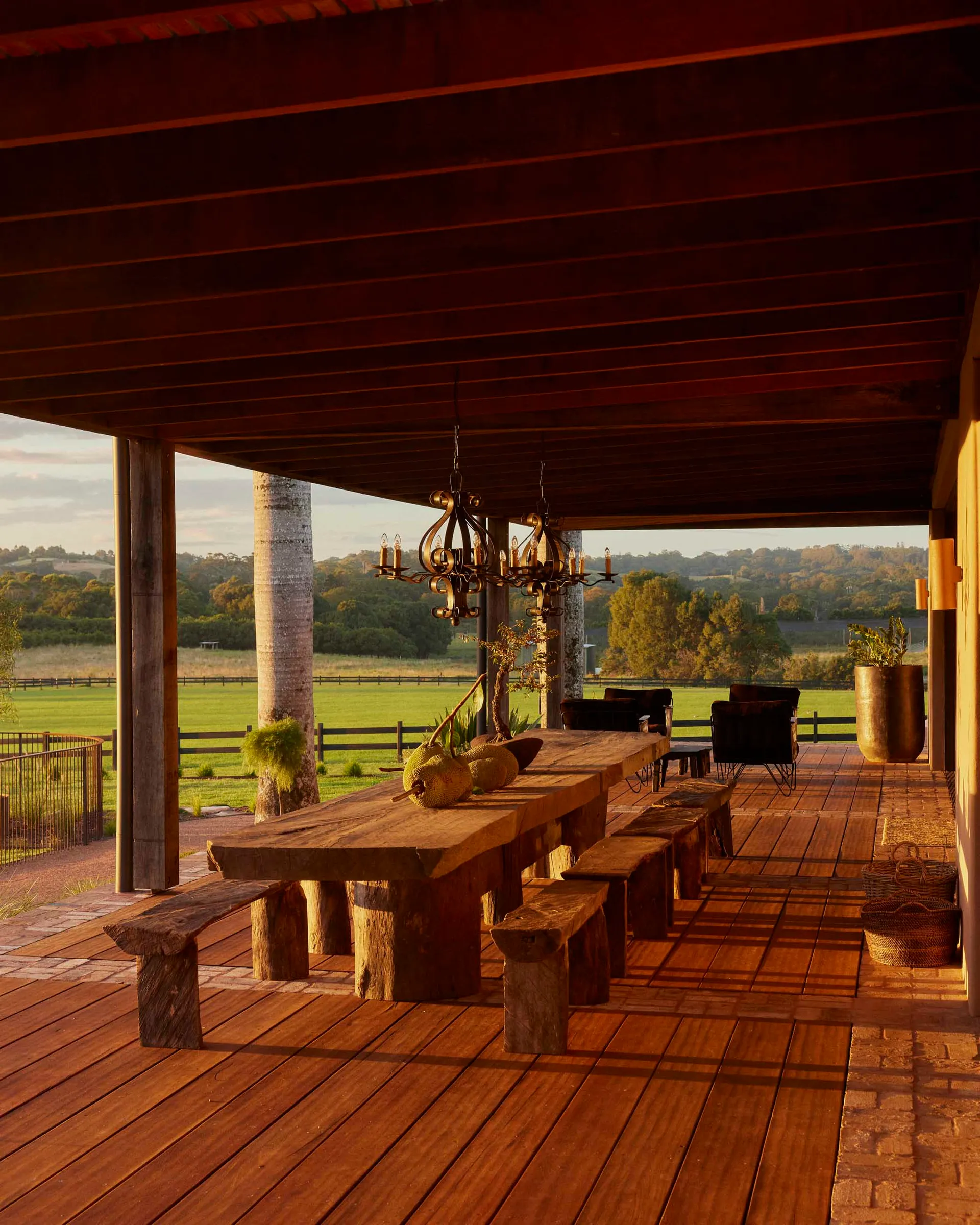 A wooden porch with furniture overlooking green fields.