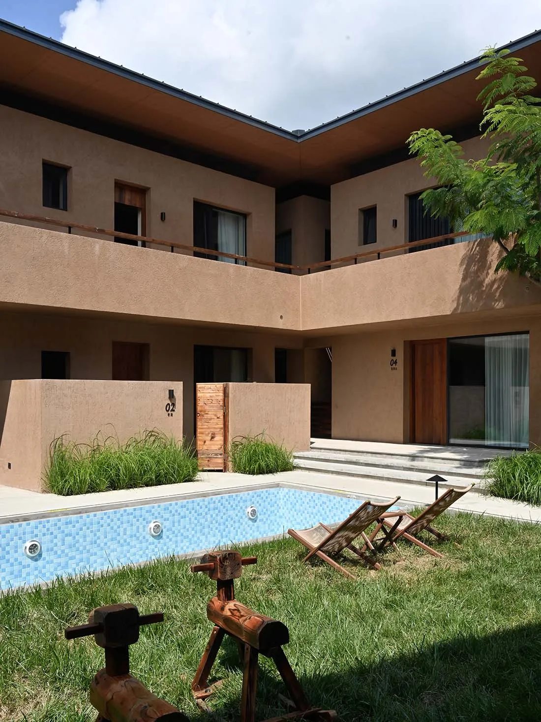 Modern concrete pool house with glass doors and pool in the yard.