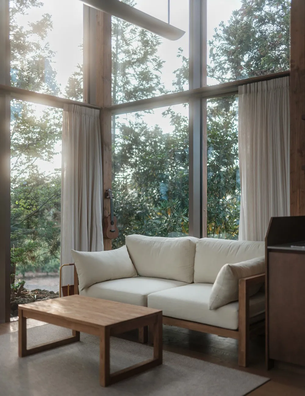 A minimalist living room featuring wood, fabric, and glass materials.