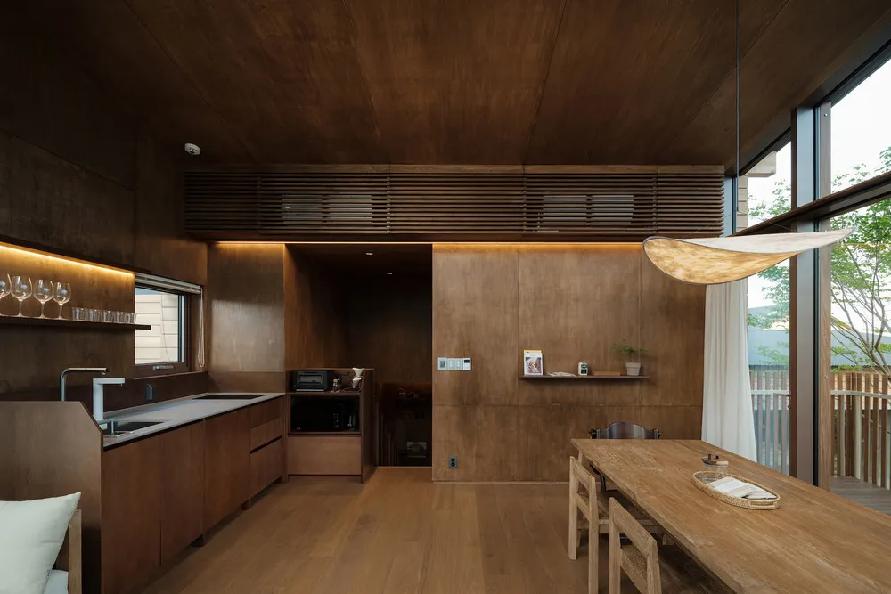 A modern minimalist kitchen featuring wooden cabinets and a large window.