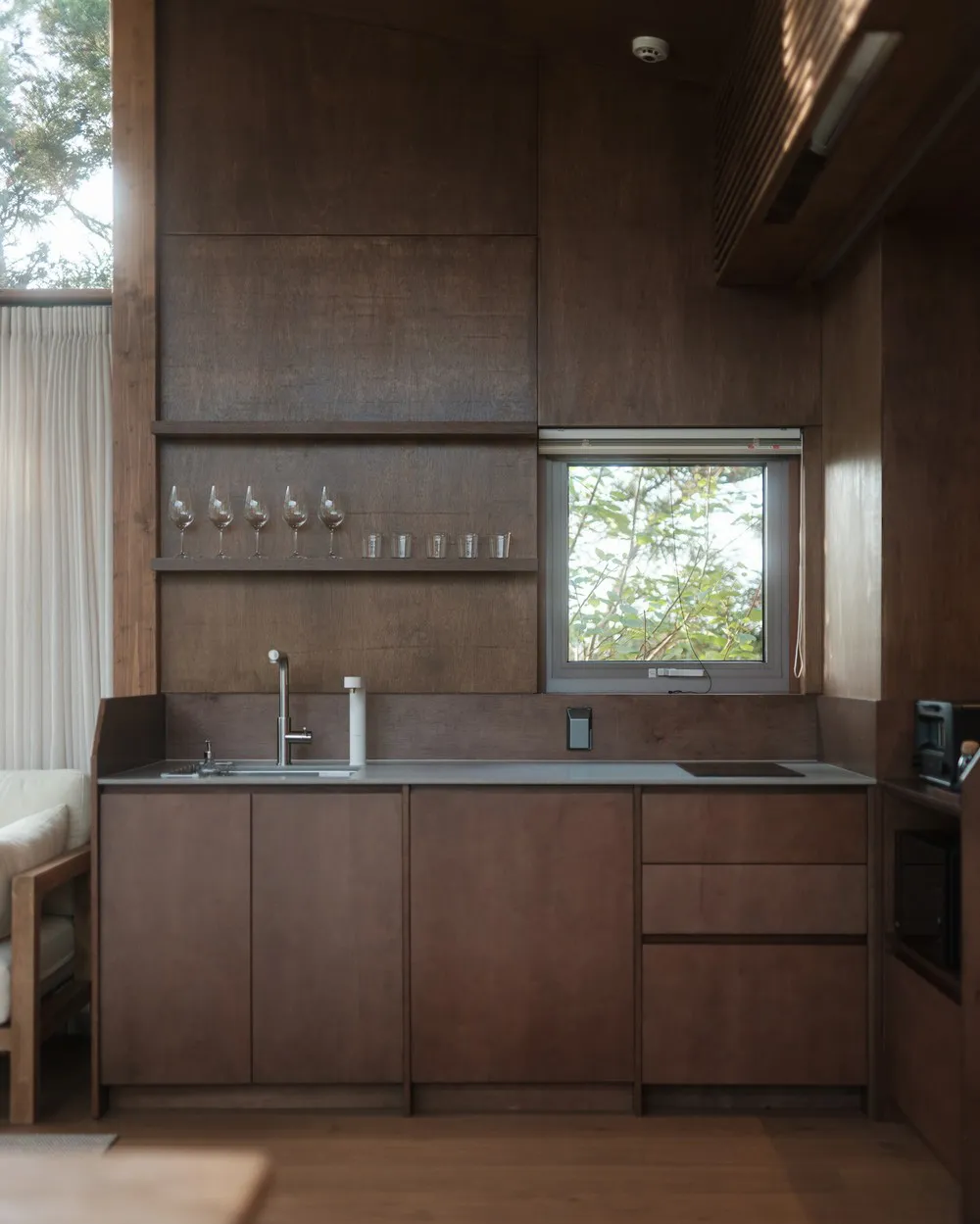 A minimalist kitchen with wooden cabinets and a glass window.