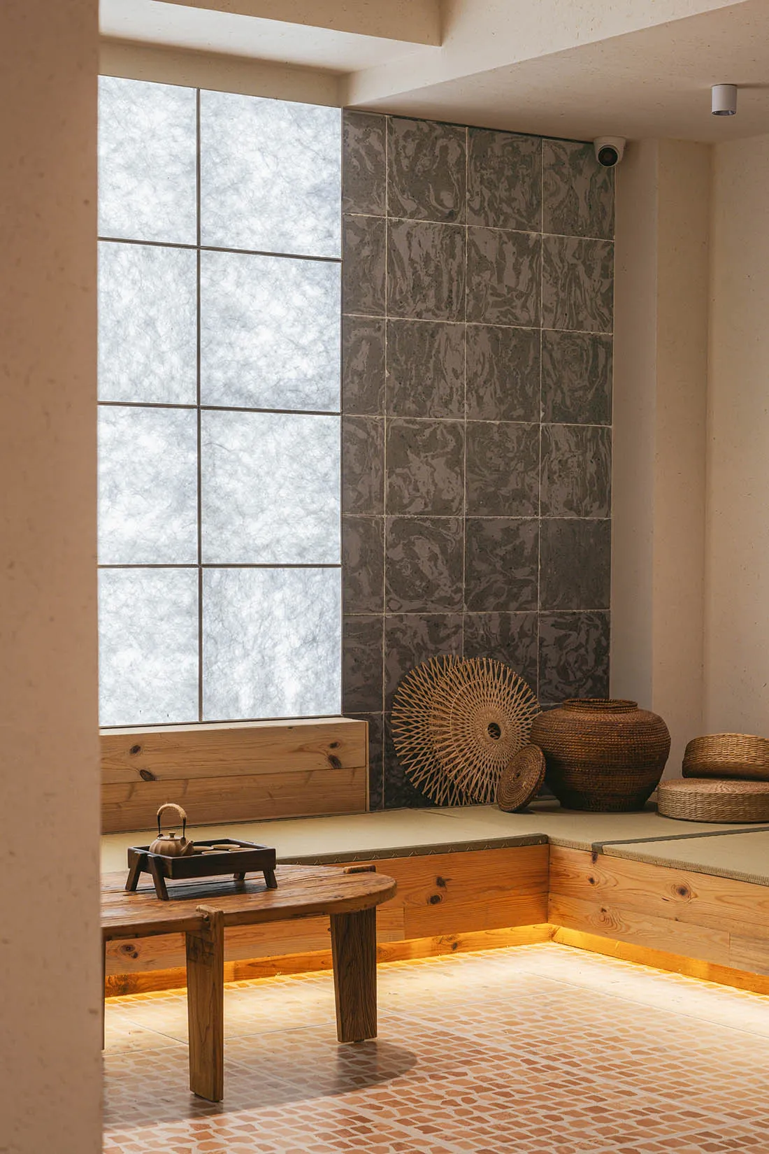 A modern minimalist interior with wooden furniture, floor tiles, and decorative baskets