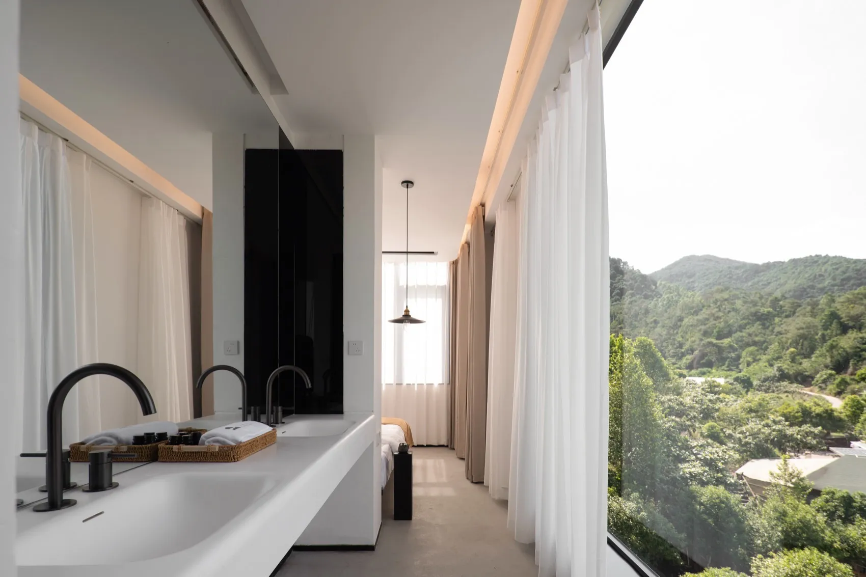 A minimalist bathroom with glass walls, concrete floor, and textile window treatments.