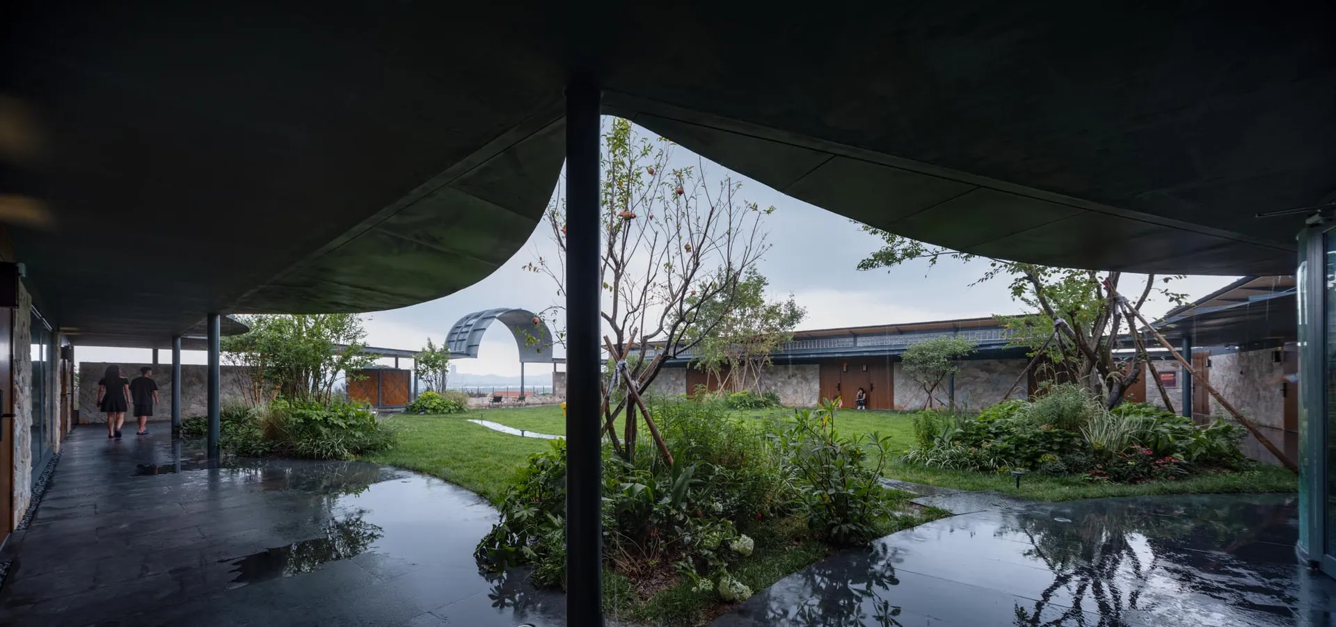 A modern garden featuring grass and plants atop a concrete structure.
