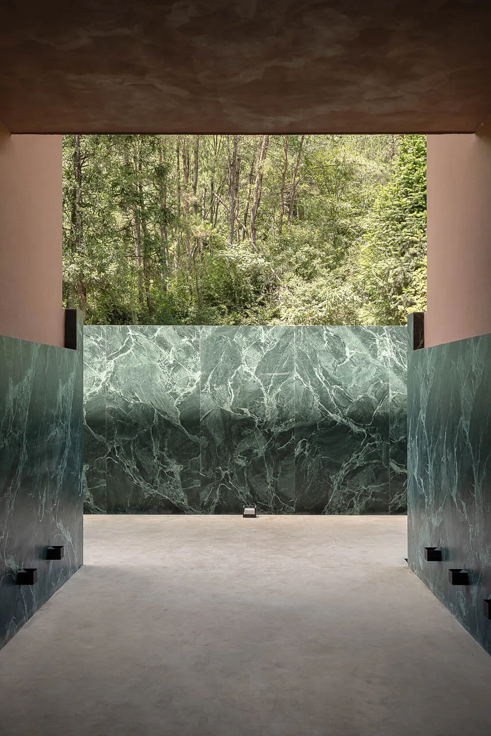 A minimalist, modern interior space featuring marble walls with a forest view.