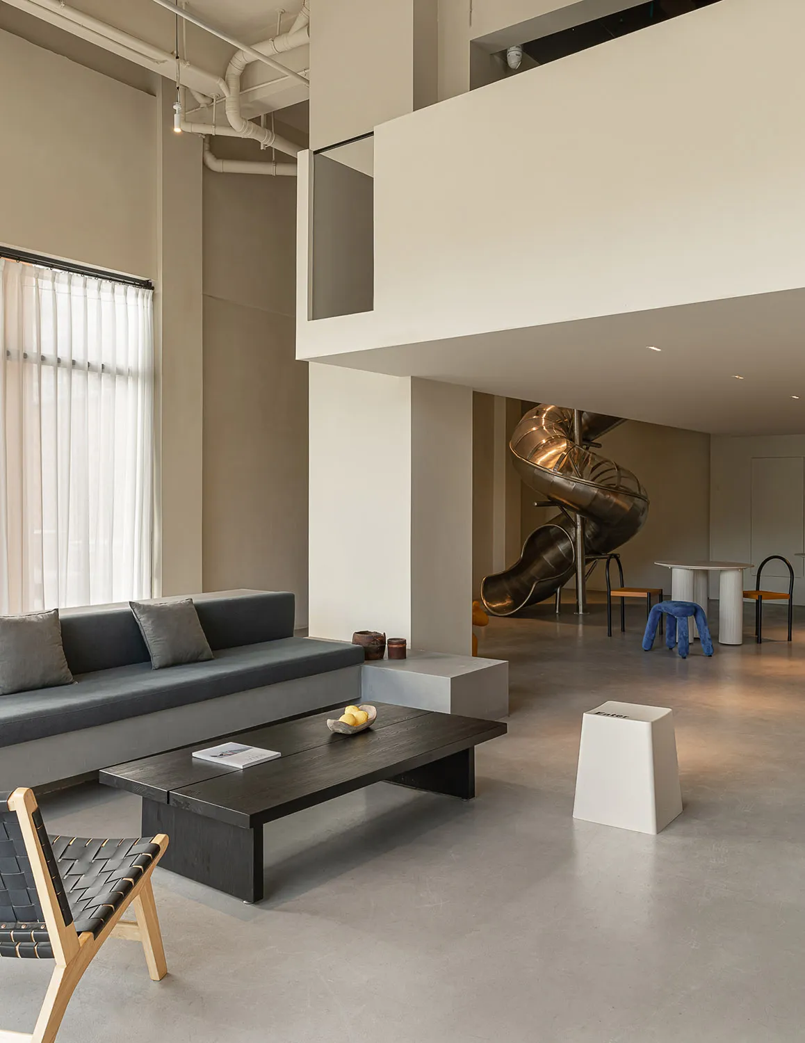 Modern office space with minimalist design, featuring concrete walls, wood furniture, and metal accents.