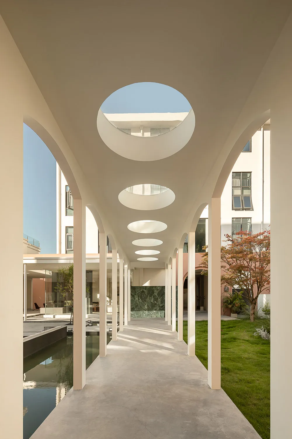 A modern residential corridor featuring concrete flooring and glass roof sections.
