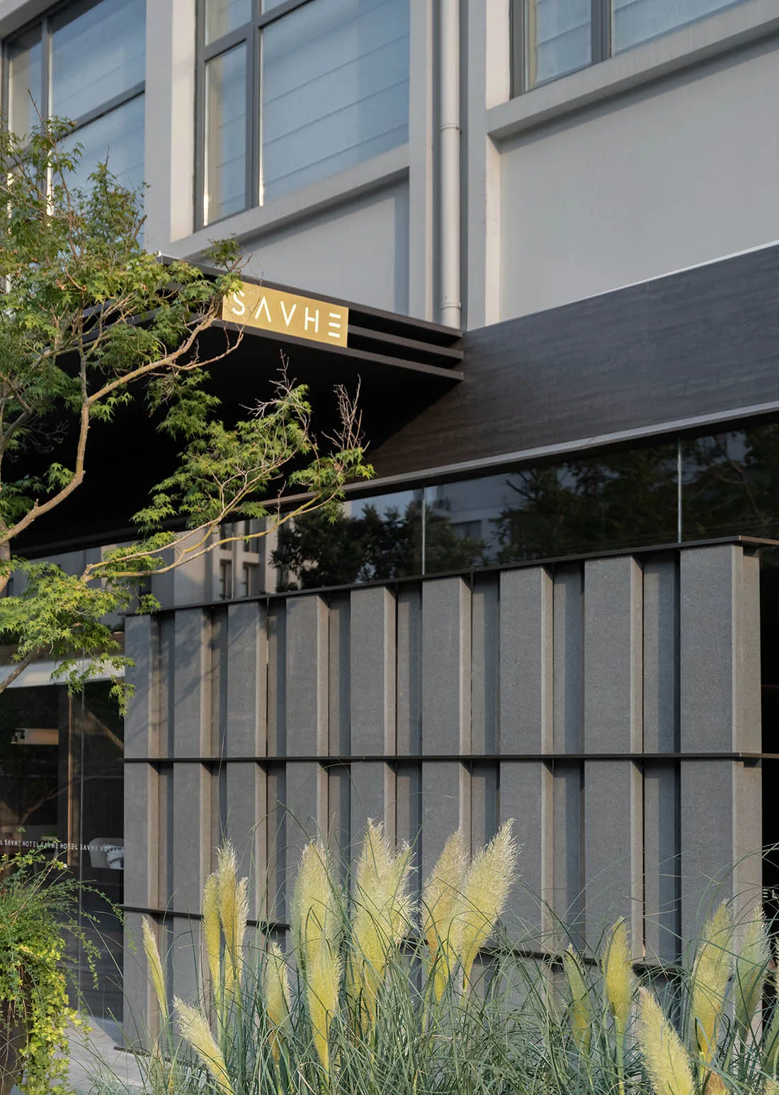 Modern hotel exterior with concrete, glass, and metal materials.