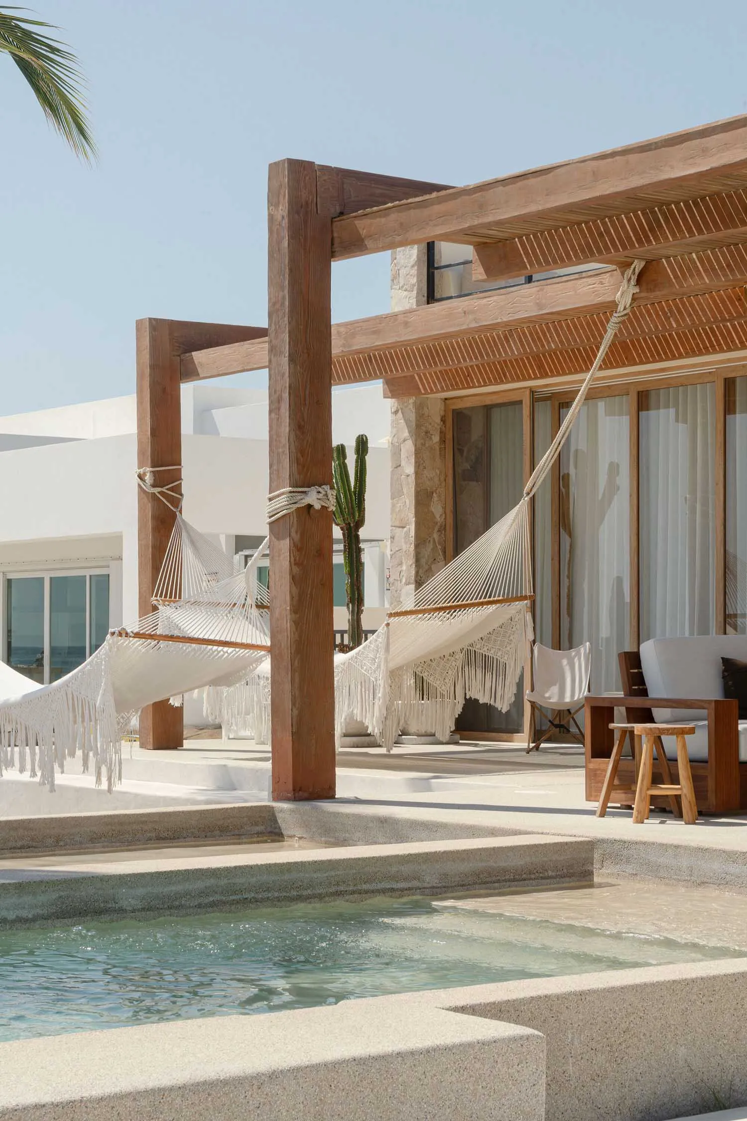 Wooden pergola with white hammocks over a concrete patio