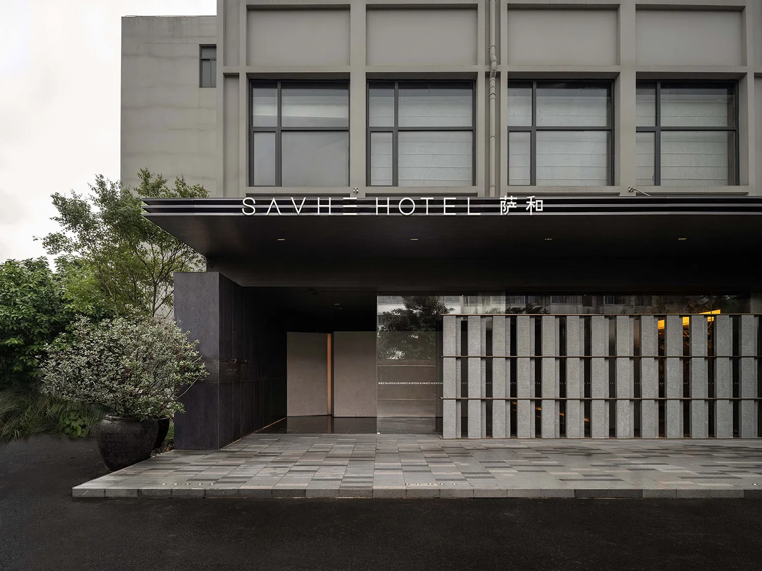 SAVHE Hotel entrance featuring concrete and glass materials.