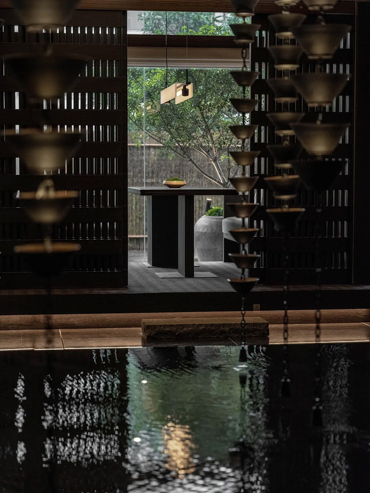 A modern spa setting with metal wall decor, featuring a minimalist design with a dark palette and a water feature.