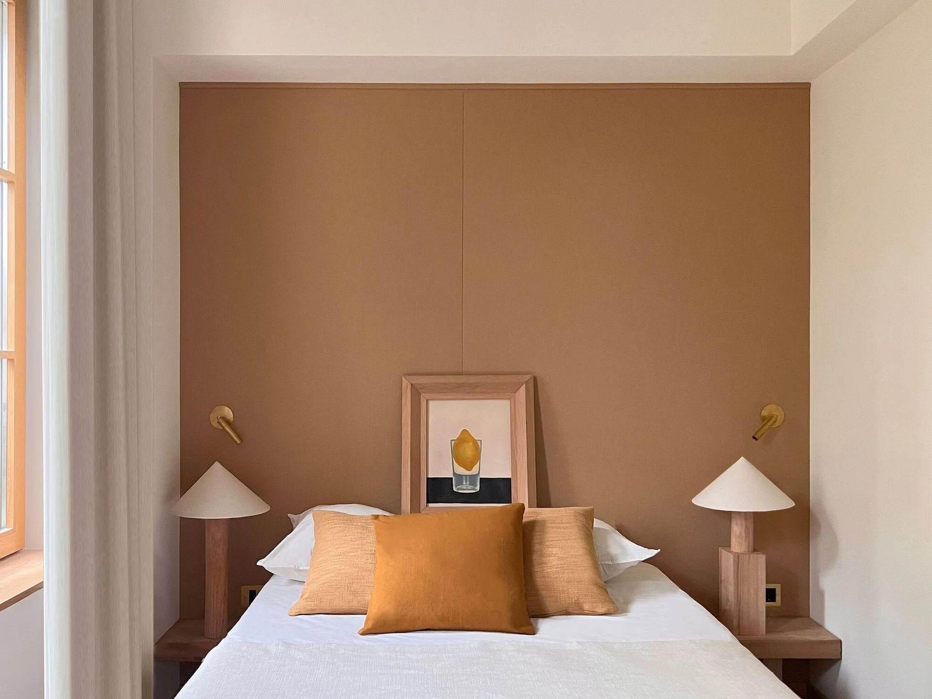 A minimalist bedroom with a bed featuring wood and concrete elements.