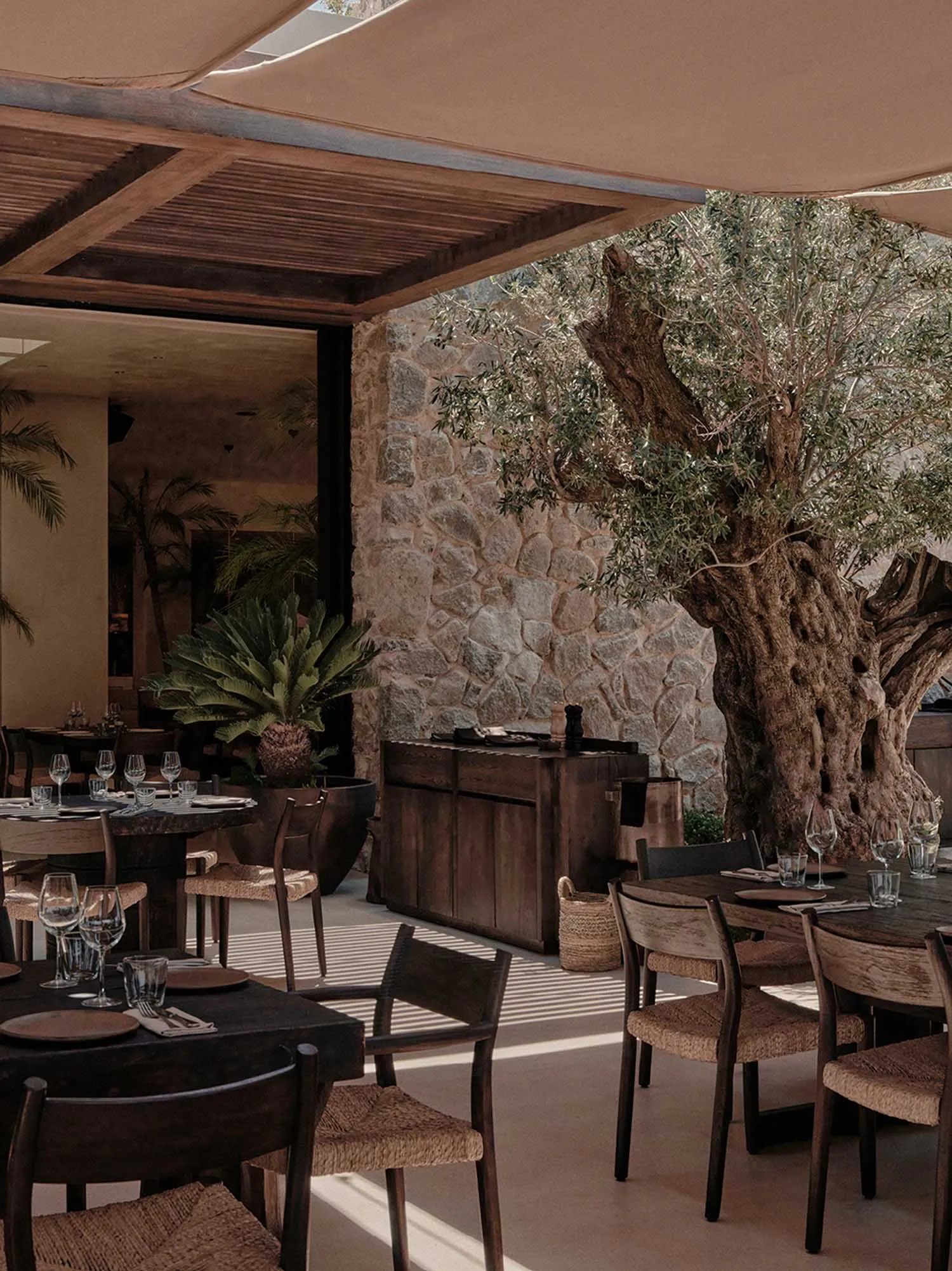 A modern restaurant interior featuring wooden furniture and stone walls.