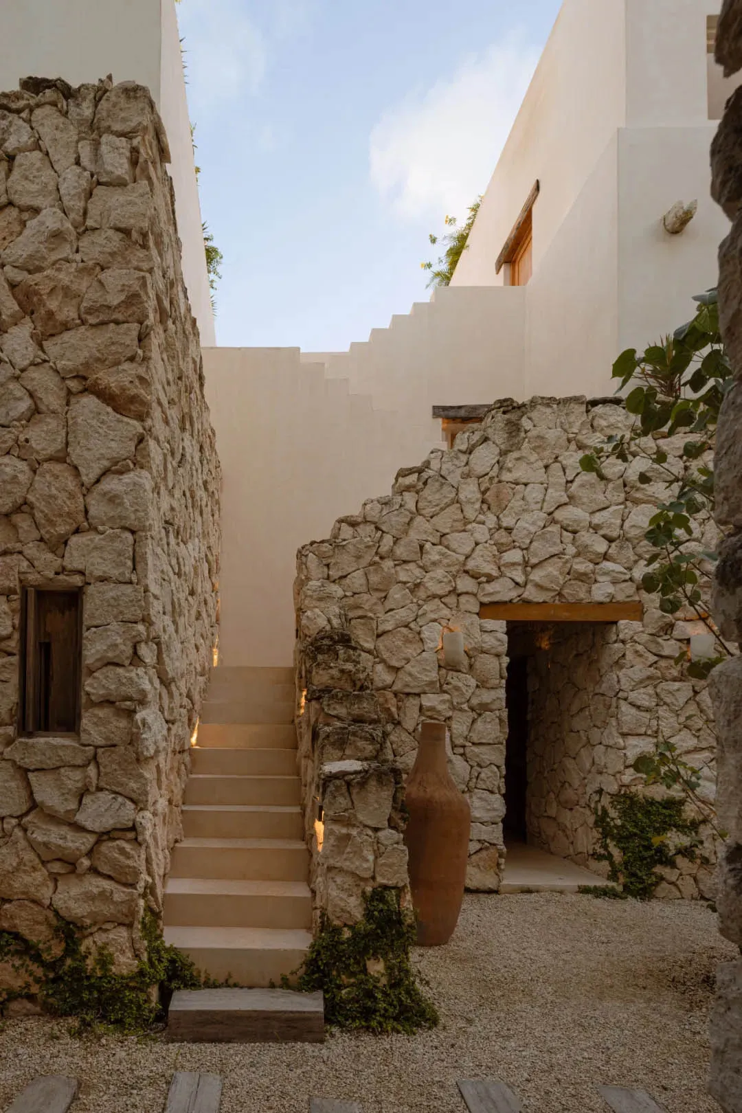A modern stone courtyard entrance with white walls and stairs.
