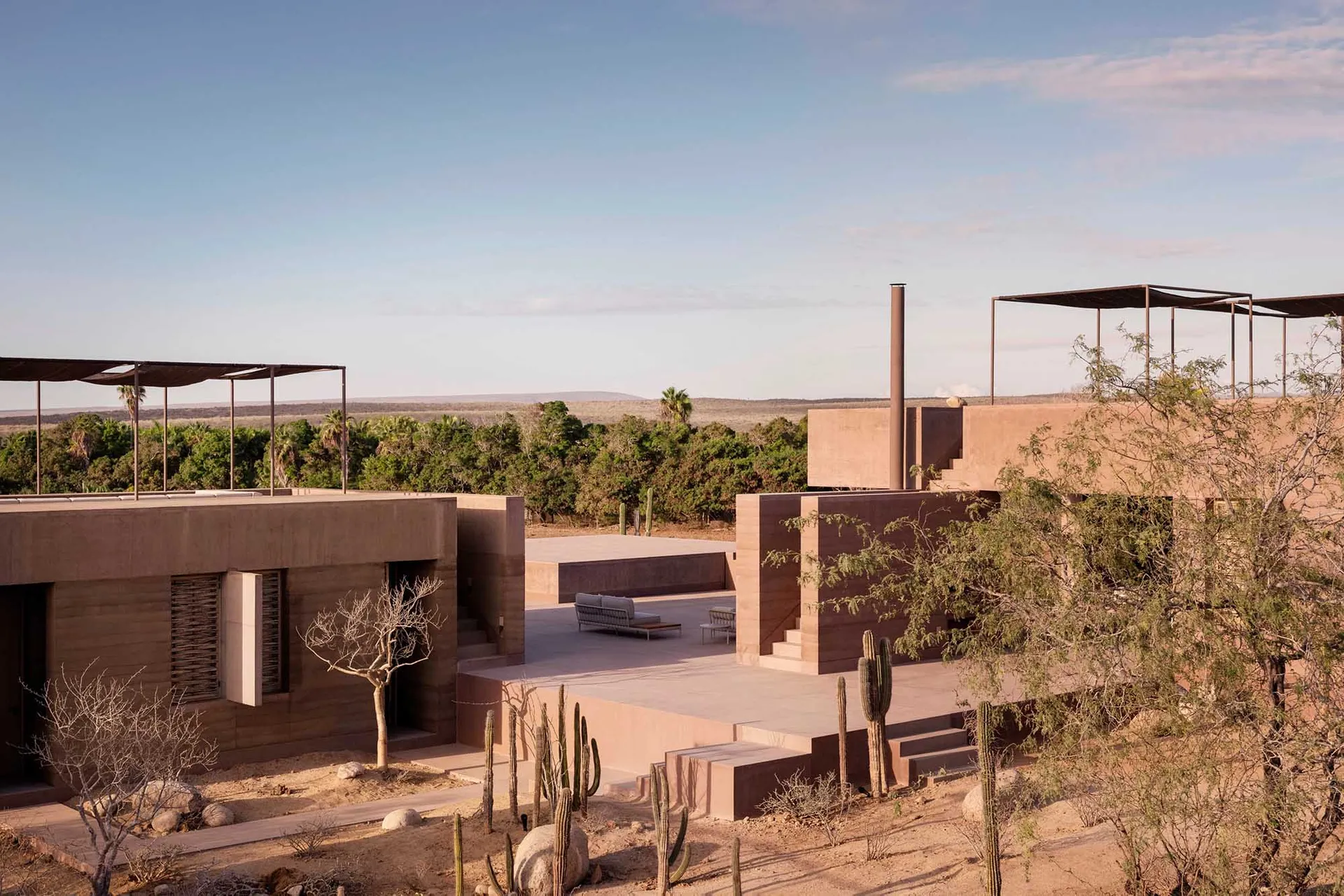Modern vacation home with sandstone exterior in a desert landscape.