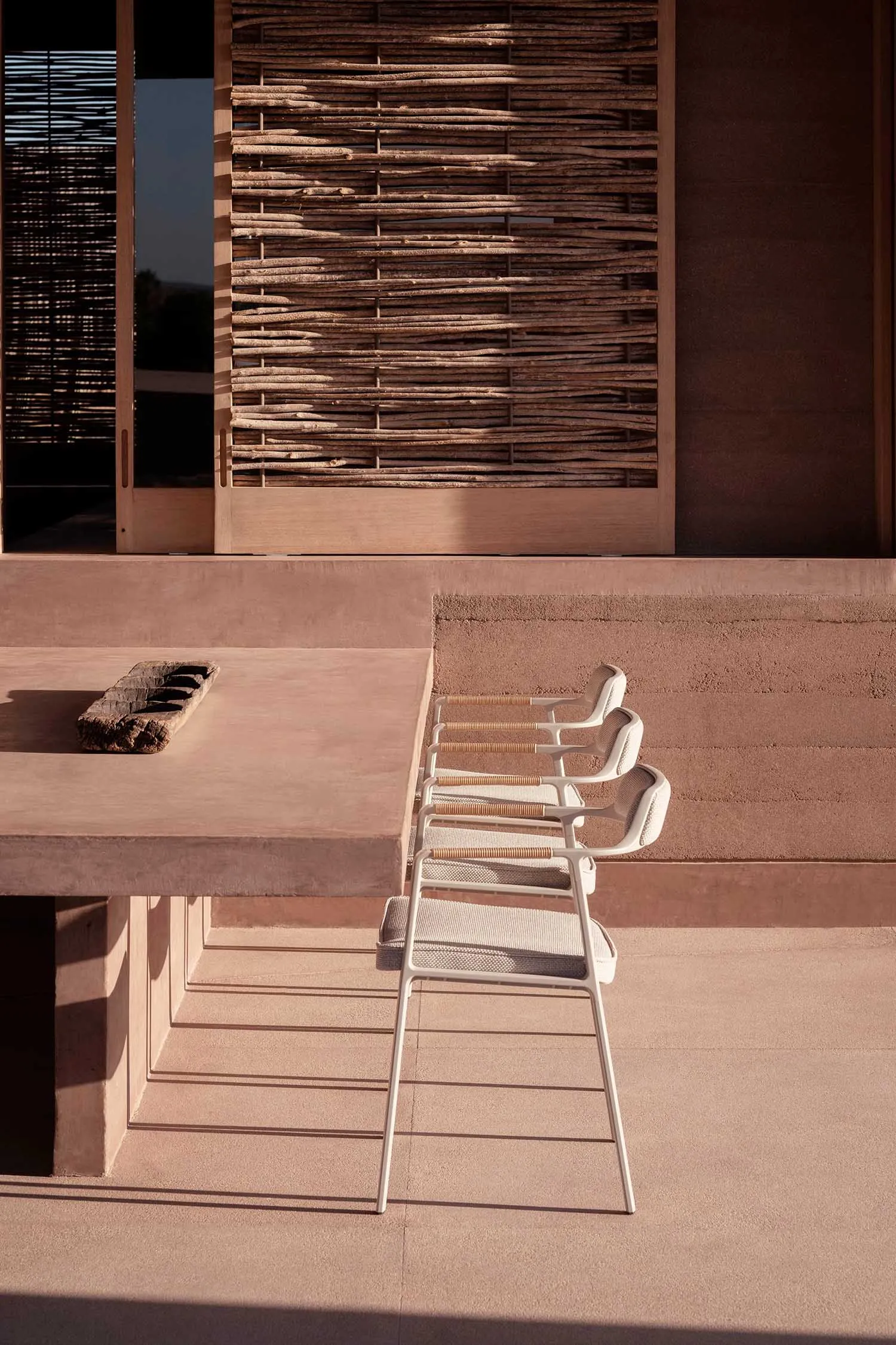 A minimalist outdoor seating area with wooden frames and fabric seats and backrests.